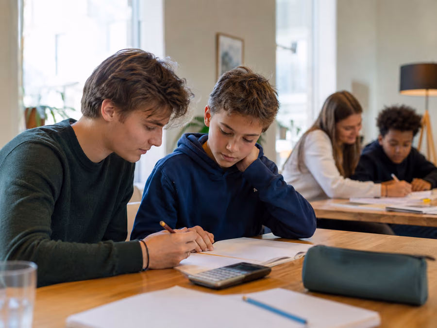 Student hjelper en ungdom med skolearbeid